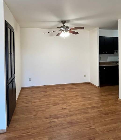 A room with a ceiling fan and wooden flooring.